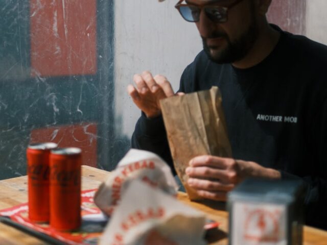 a man sitting at a table and eating street food