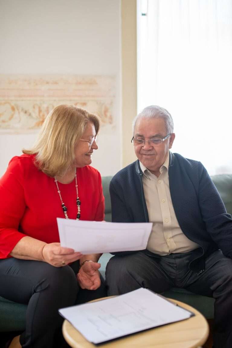 an elderly man and woman sitting on the couch while having conversation