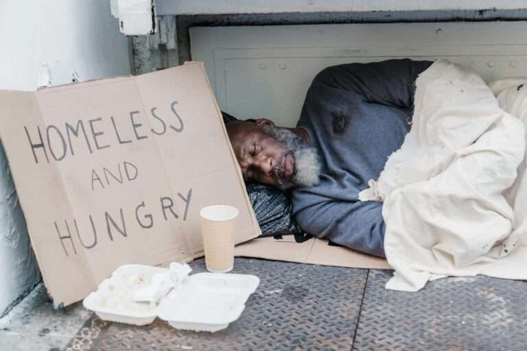 photo of a homeless man sleeping near a cardboard sign