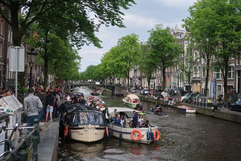 crowded streets and boats on the canal in amsterdam netherlands