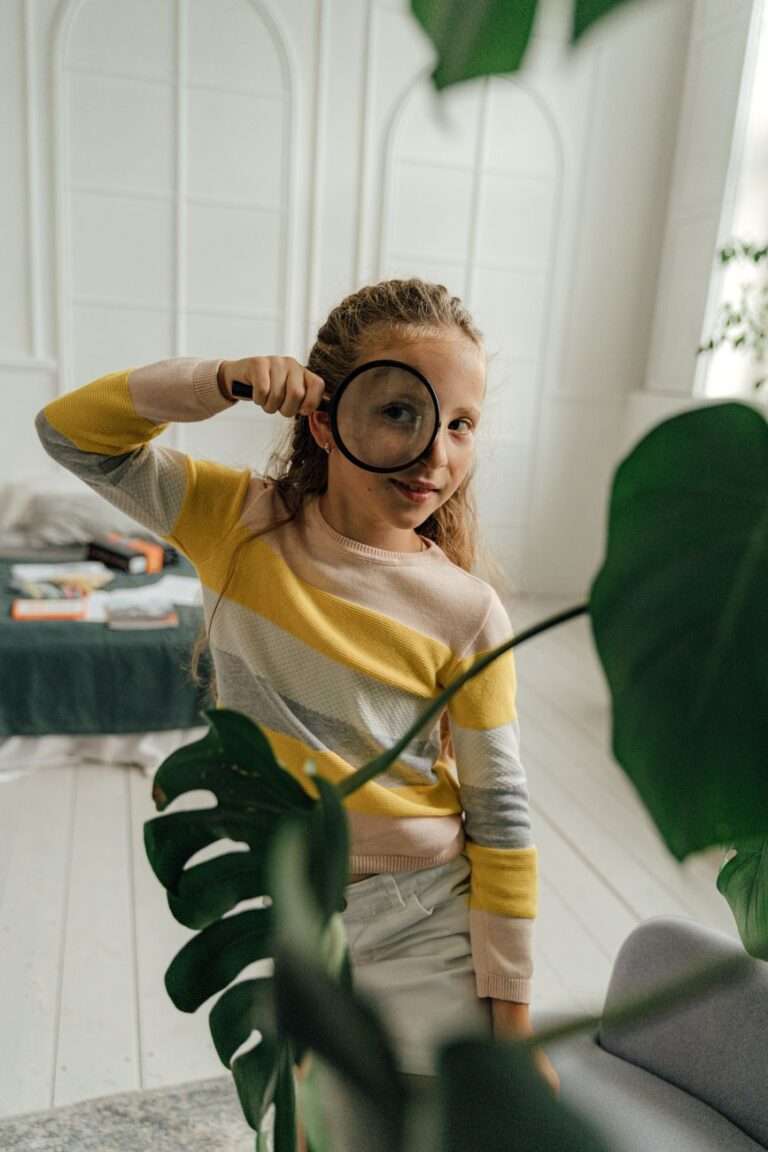 girl in sweater using magnifying glass